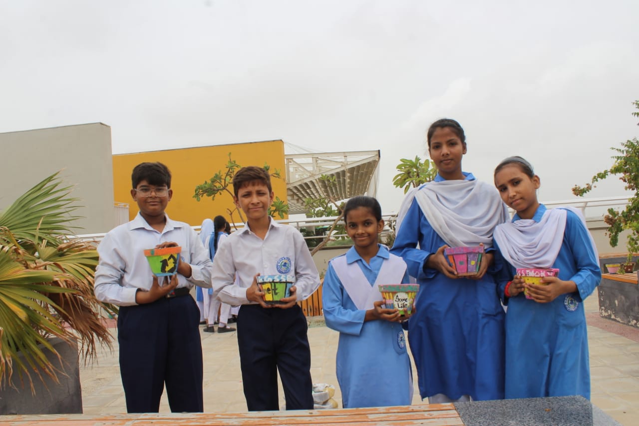 A group of students poses after the vegetable garden activity where the students planted local vegetables in pots painted by themselves.