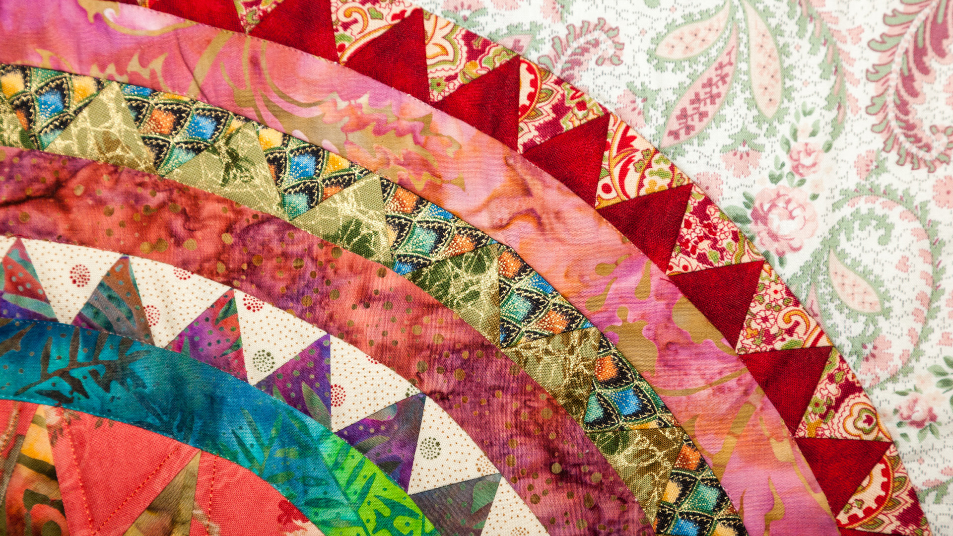 An image of a colorful patchwork quilt with a triangle pattern.