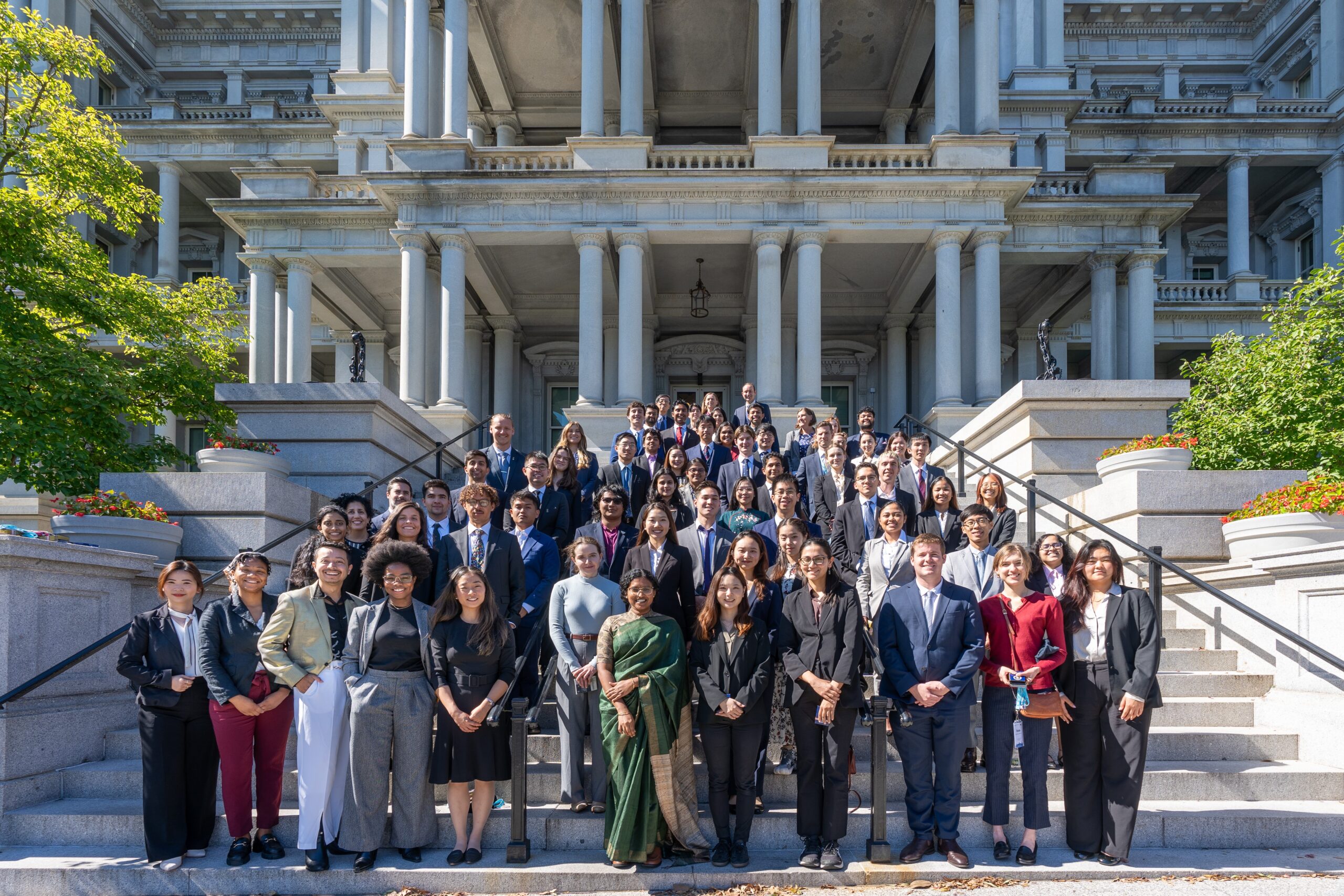 A large group of formally dressed people standing on the steps of an ornate, columned building.